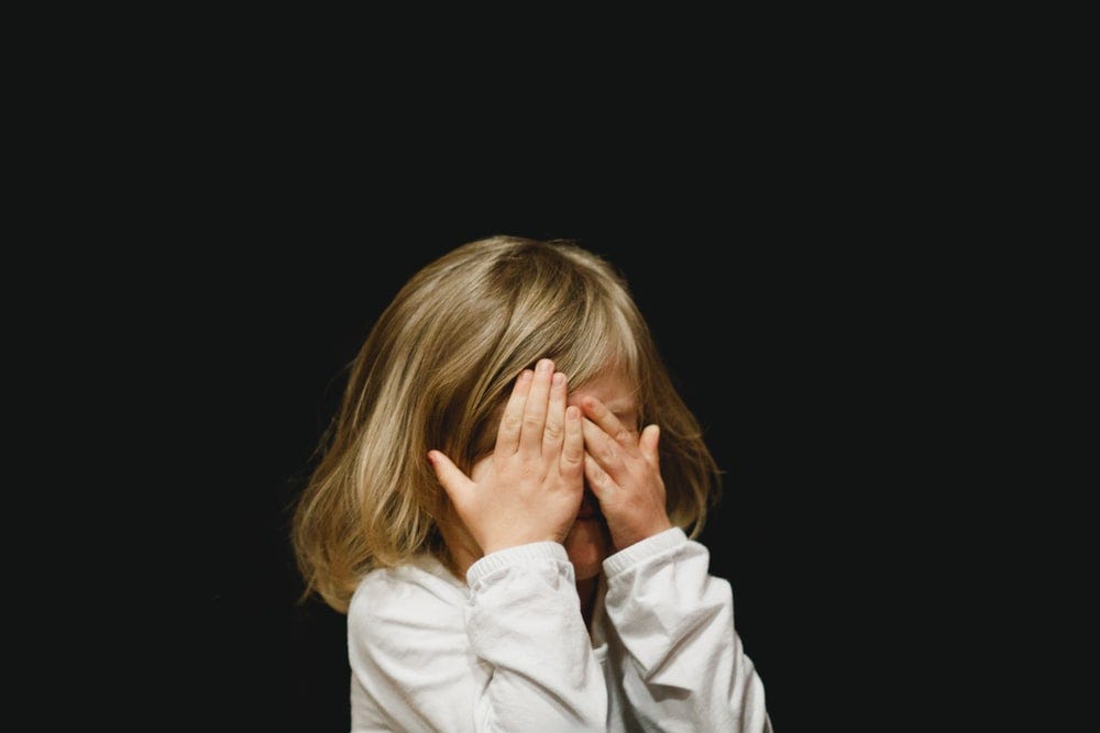 A child covering her eyes with her fingers.