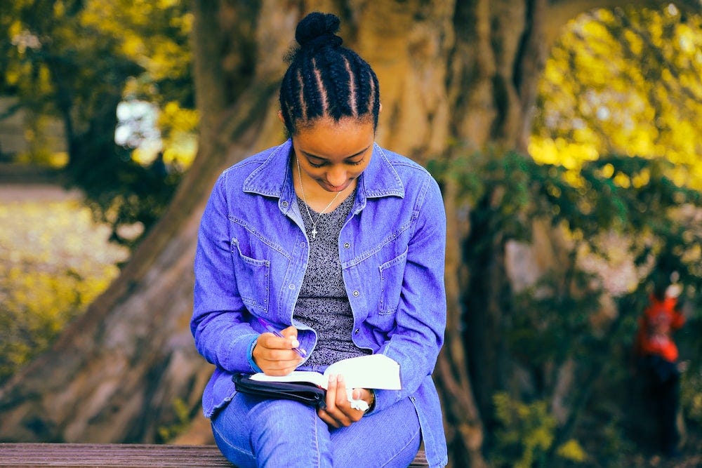 young Black person writing in their notebook