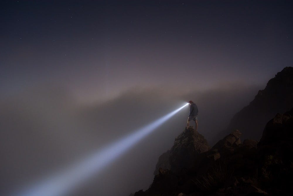 Hiker wearing a headlight on a foggy mountain side