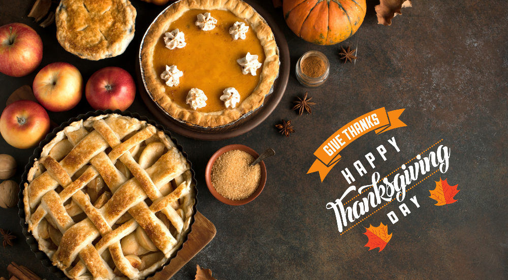 A dark background with a pumpkin pie, a apple pie, some fruit, and a white phrase