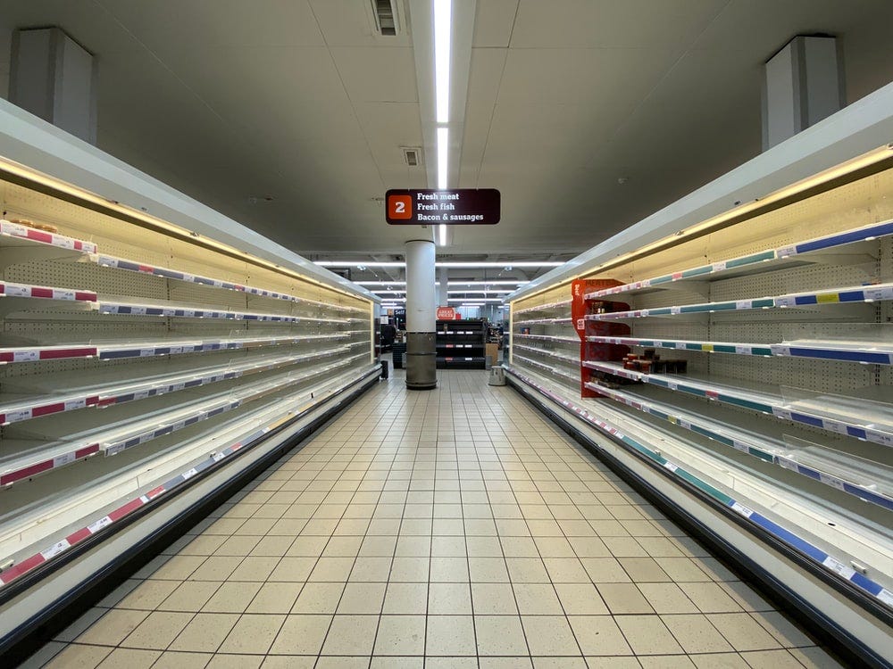 An aisle of fresh foods is seen to be completely emptied out in a grocery store.