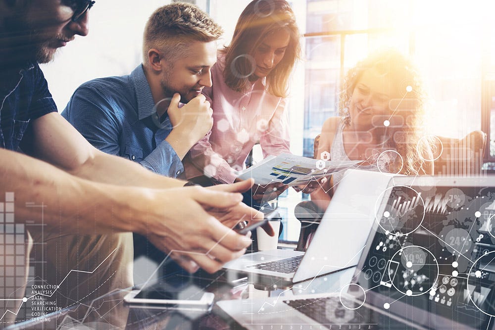 People working together with computer and phone on table.