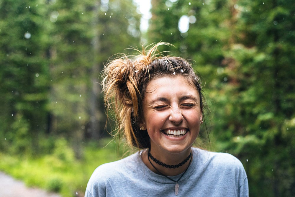 Young girl enjoying the rain outdoors and grinning or laughing with joy . photo by Jamie Brown 