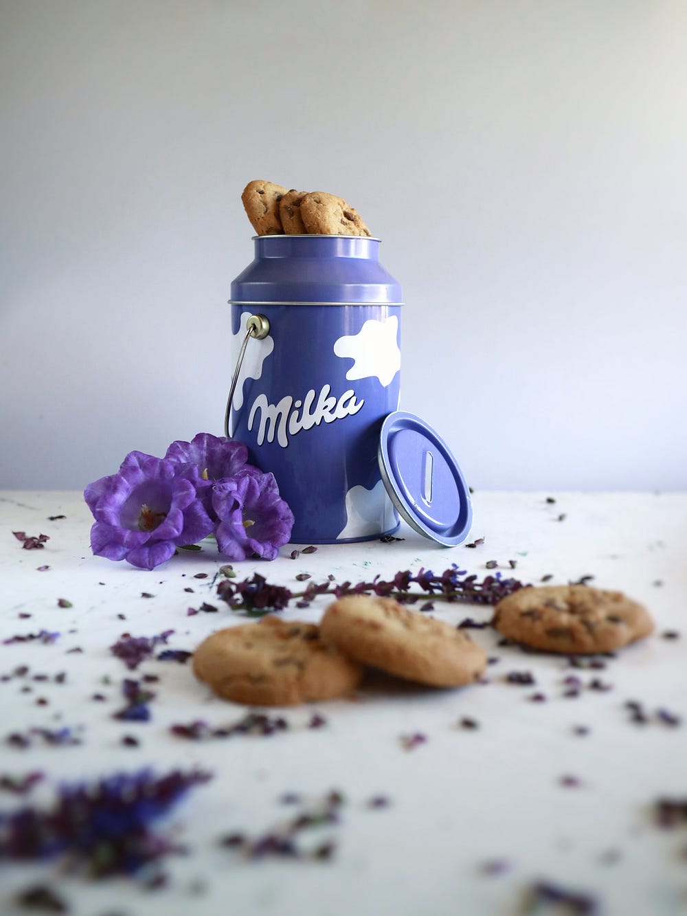 Cookies in a purple Milka trademark jar with purple flowers near it