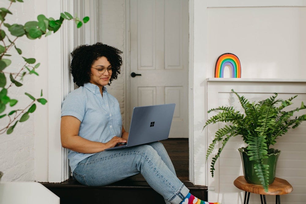 A woman sits on the floor using a laptop