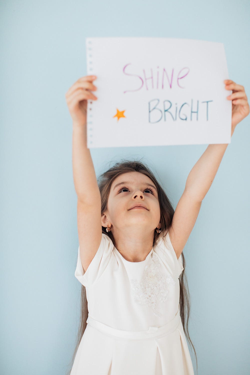 Little girl holding up a sign that says ‘Shine Bright’