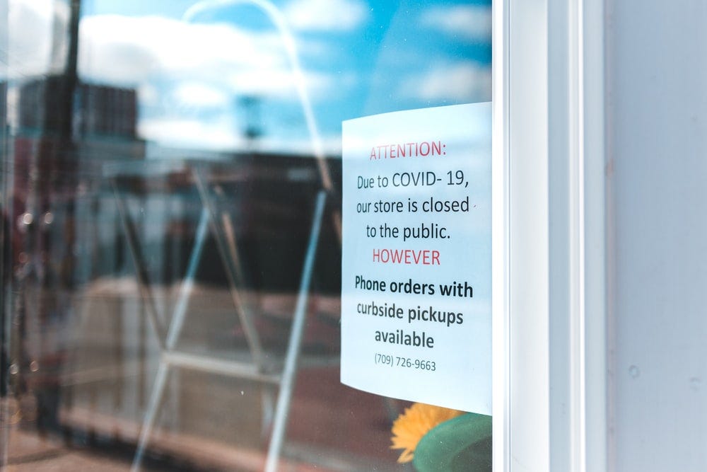 A sign is put up outside a closed store, informing that there are phone and pickup options available.