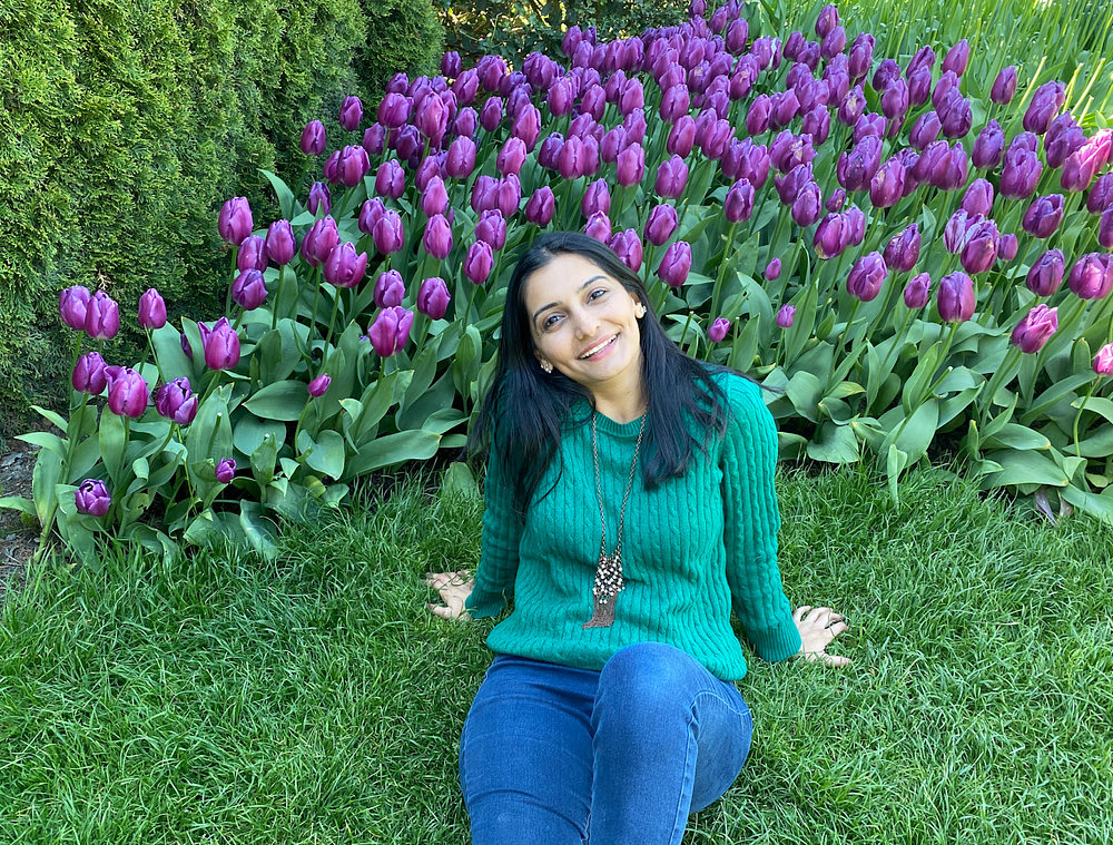 Maham sitting in the grass in front of some purple tulips