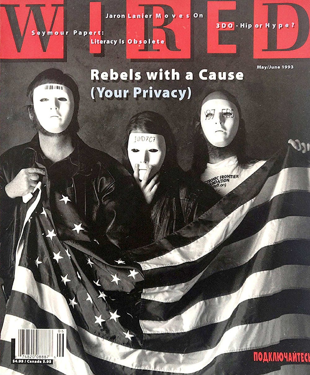 The cover of Wired 1.2, depicting three cypherpunks in white masks holding a white flag. The cover text reads “Rebels With a Cause (Your Privacy)”