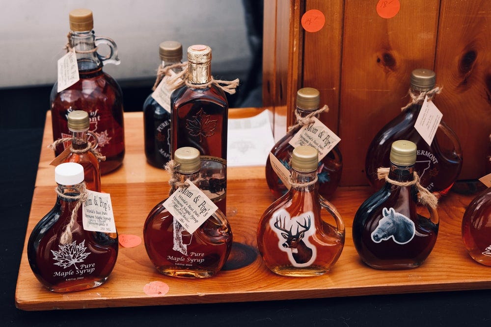 Multiple bottles of maple syrup on a table.