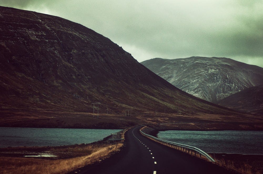 A wide open road with a mountanous background