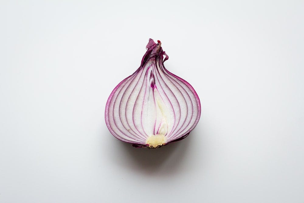 A side cut of an onion with purple skins
