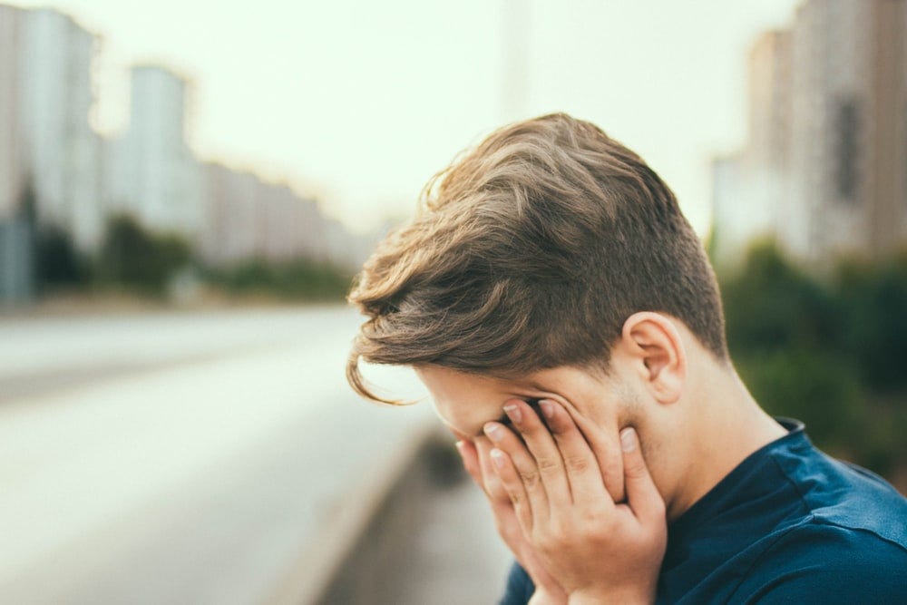 A man pressing his fingers on to his face as if he is very tiredness/ fed up.