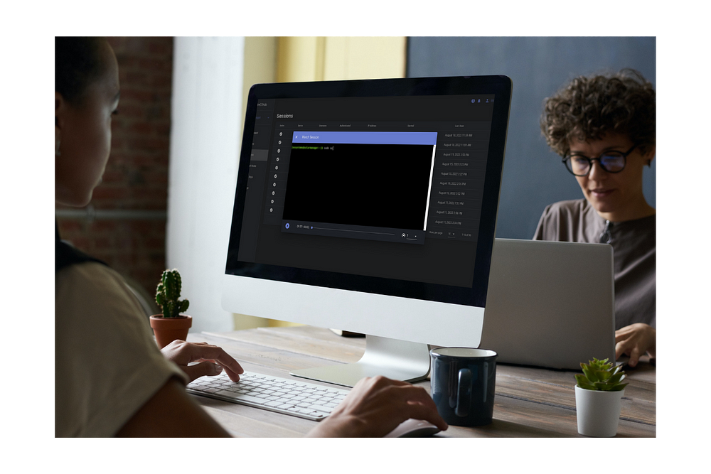 Jovem mulher em um escritorio em frente a um monitor utilizando o ShellHub para reproduzir a gravação de uma sessão.