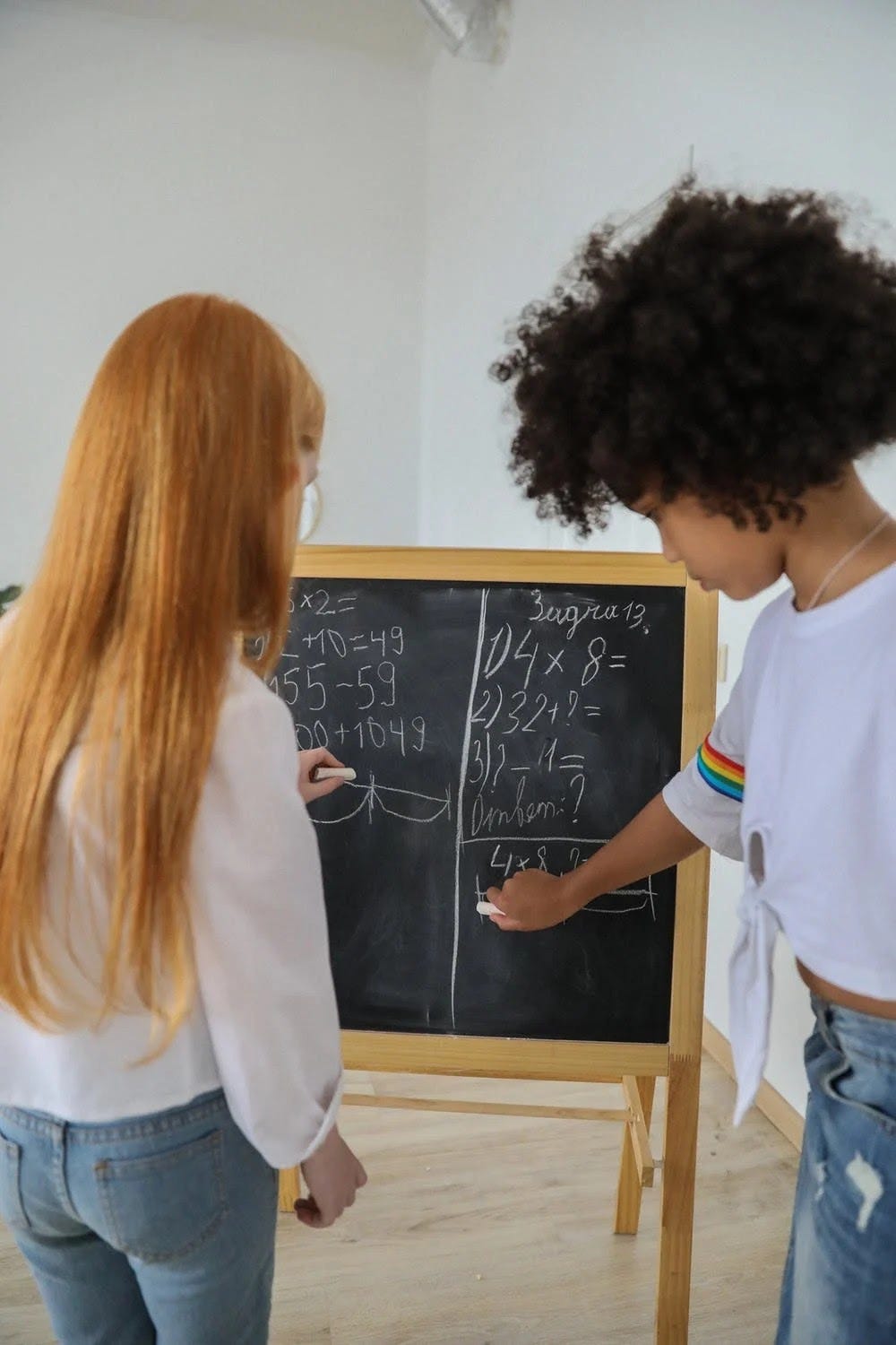 A boy and a girl writing on a black board
