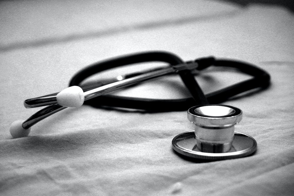 A black and white photo of a stethoscope on a white colored cloth.