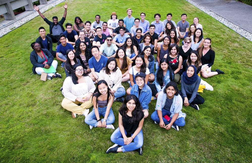 The Fung Fellows sitting in a triangular formation on grass.