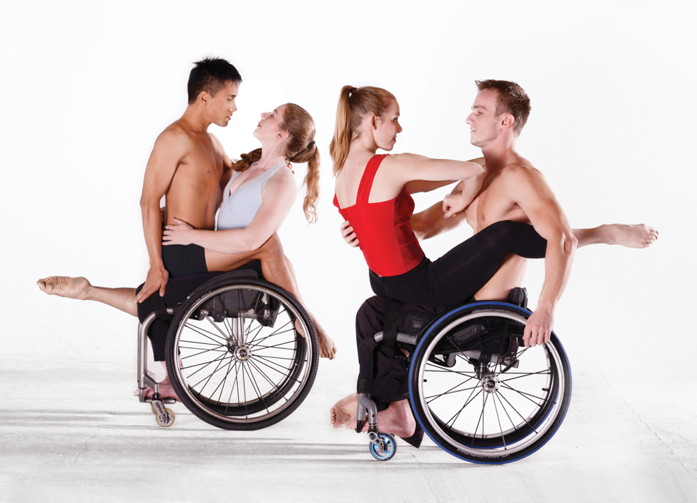 Two nondisabled dancers straddle the laps of two wheelchair users in two couples: one pair compassionate and softly embracing, one pair confrontational and polarized. Gazes are intent and colors are spare and stark: red, gray, and black, the masc dancers shirtless.