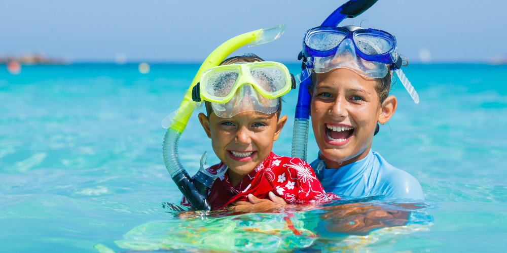 Two boys wearing snorkels and snorkles in the ocean.