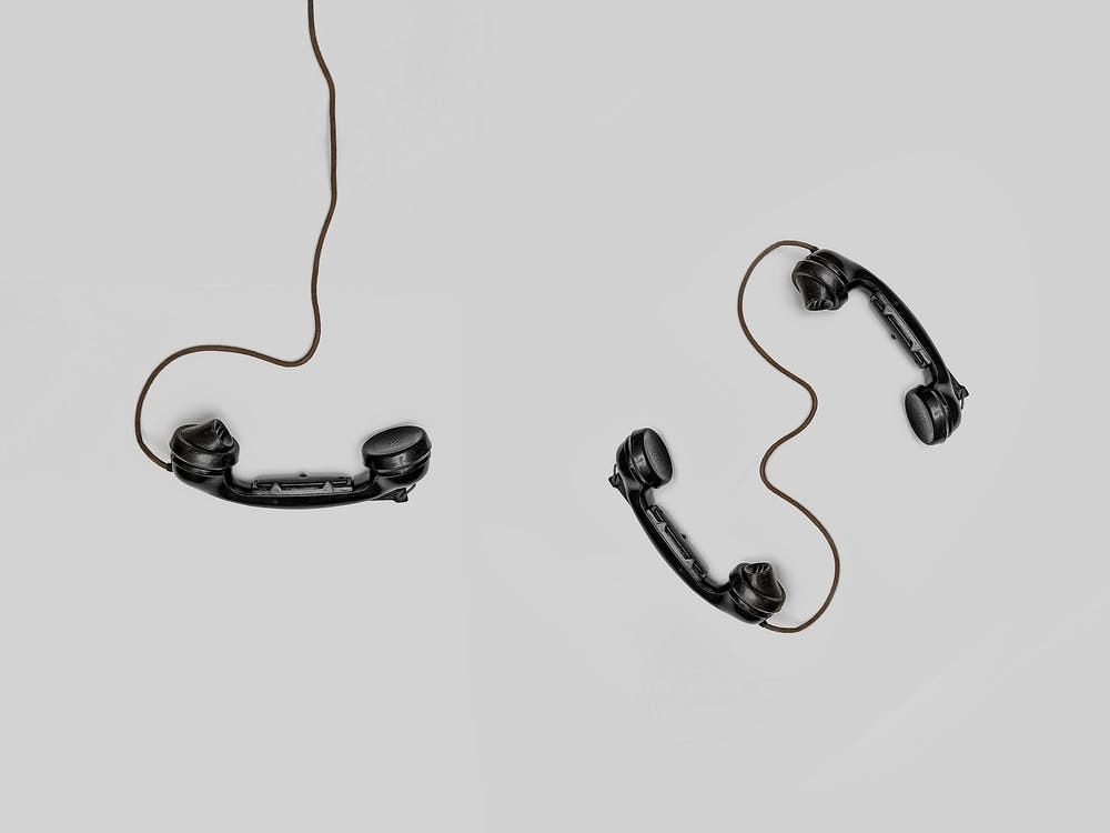 Three black retro wired telephones against a white background