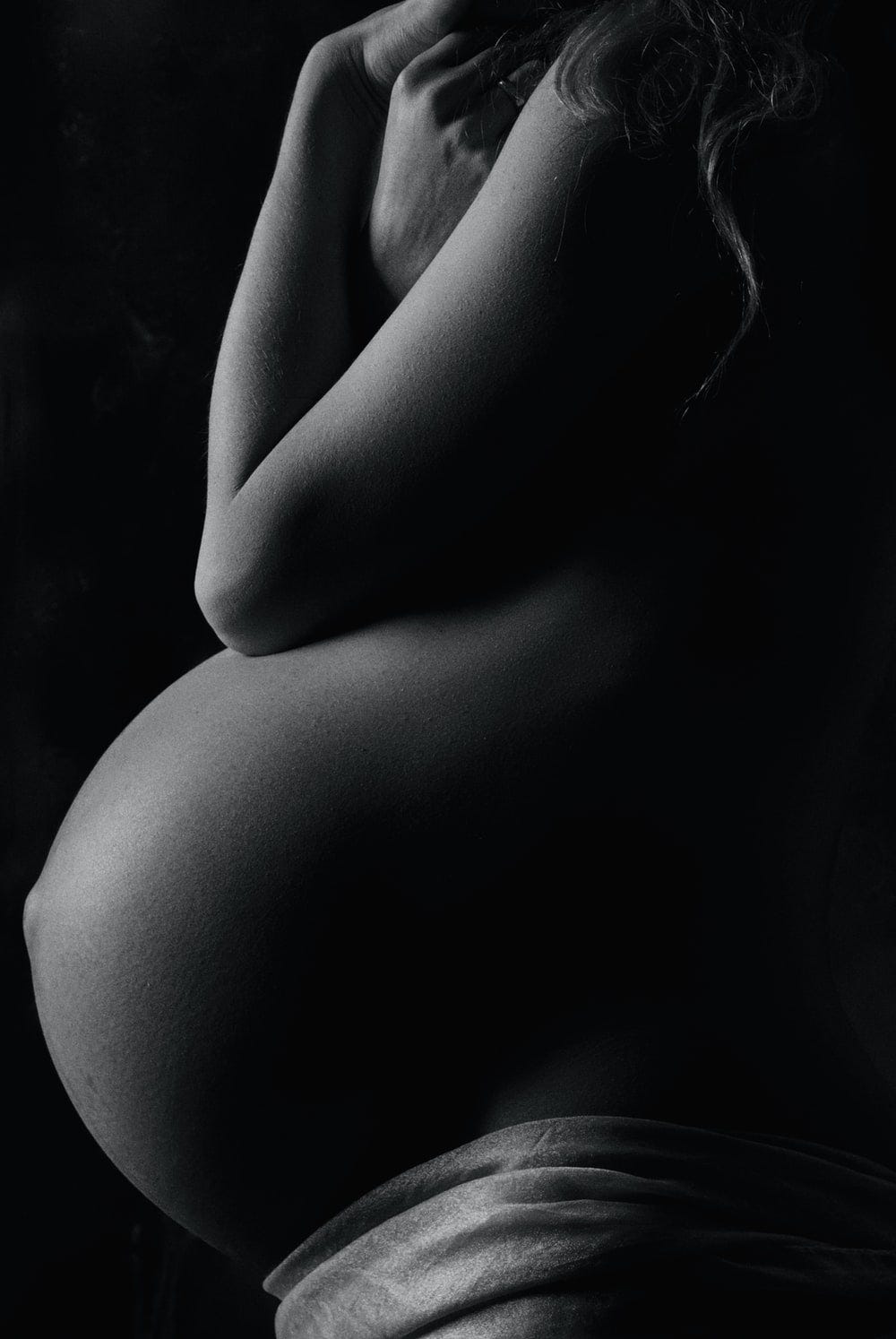 Black and white image of a pregnant woman’s belly.