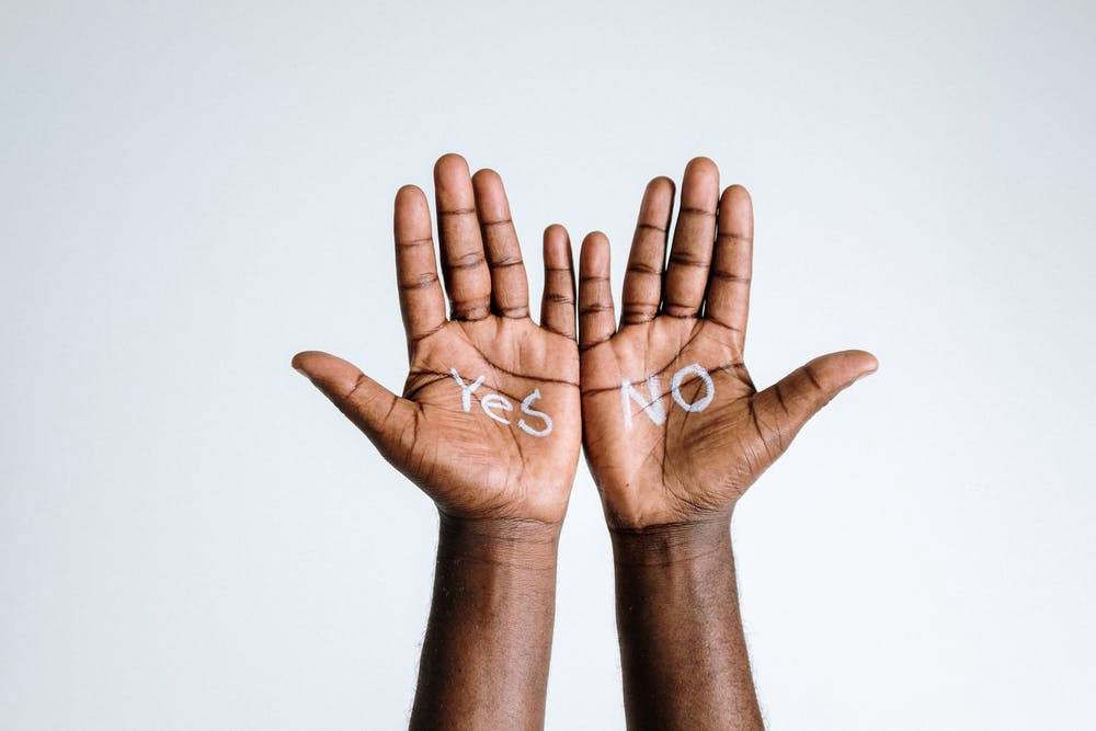 A photo of two hands, one with the word “yes” and one with the word “no” written on their palms.