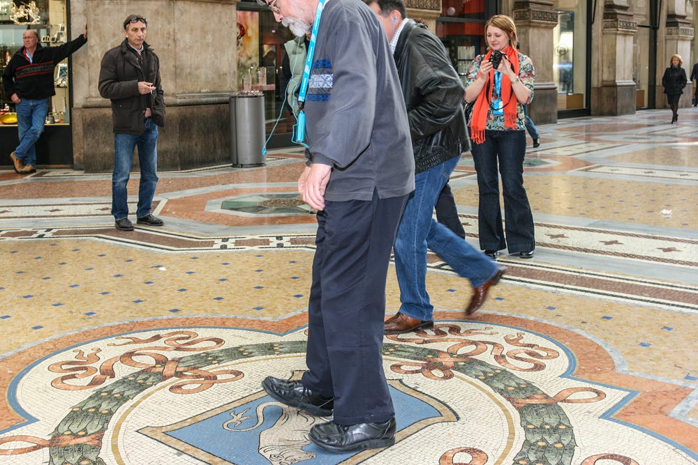 A man sets his heel on the mosaic bull in the middle of the Galleria Vittorio Emanuele II and gets ready to spin.