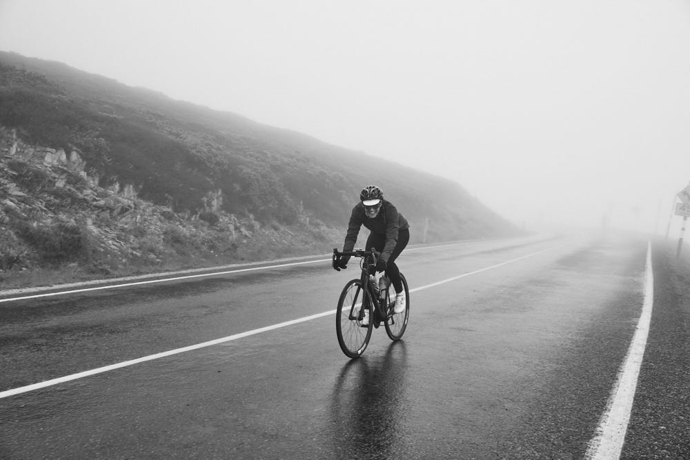 A woman riding a bicycle on a misty road, smiling