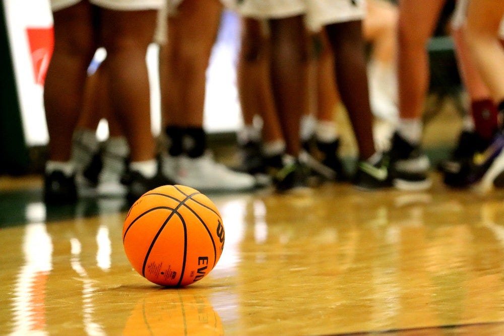 Basketball lies on the court during a high school basketball game timeout.