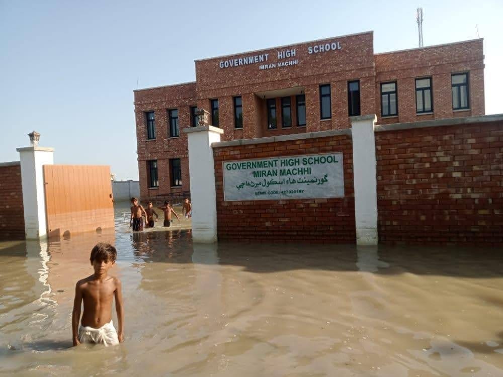 A small group of young boys wade in nearly hip-high waters outside of Pakistan’s Meeran Machhi High School.