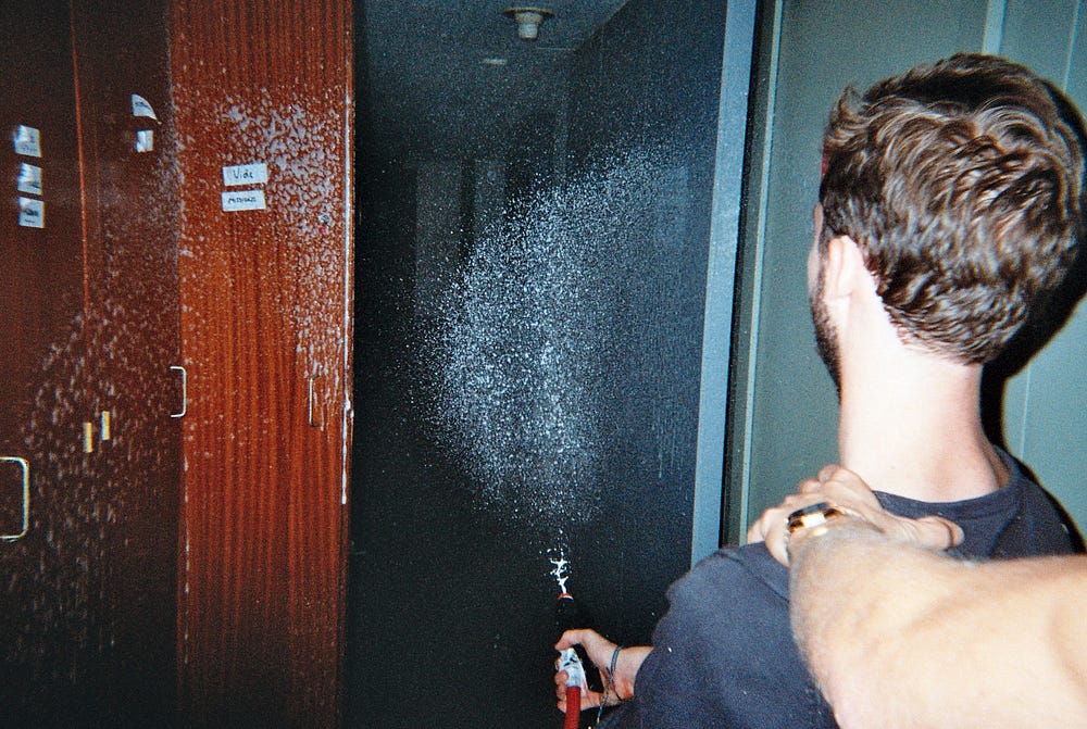 A young man playing with a fire extinguisher in a corridor