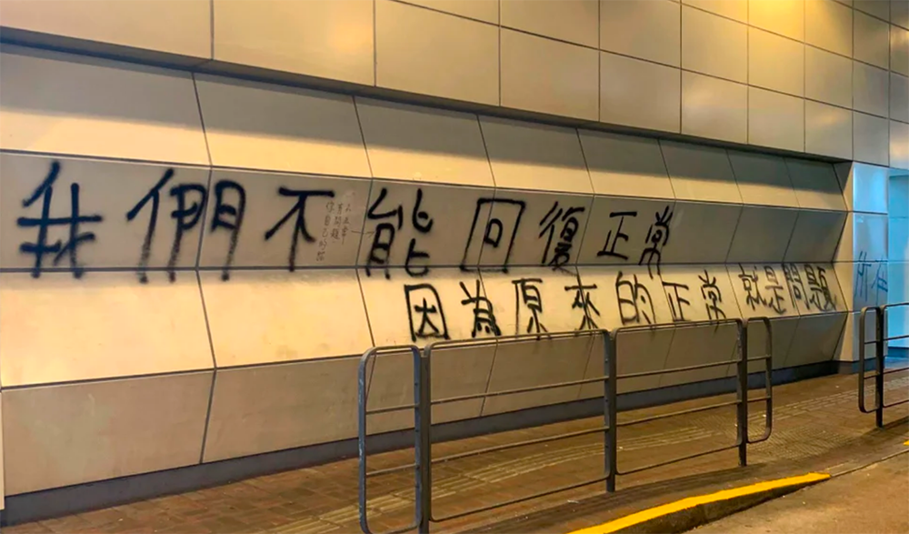 A graffiti on a wall that reads in Chinese: “We can’t return to normal because the normal we had was precisely the problem”