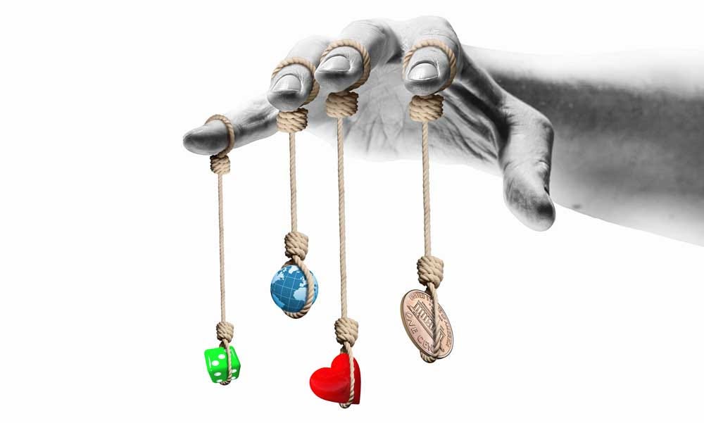 hand with a string on each finger that dangles a heart, dice, a globe and a coin