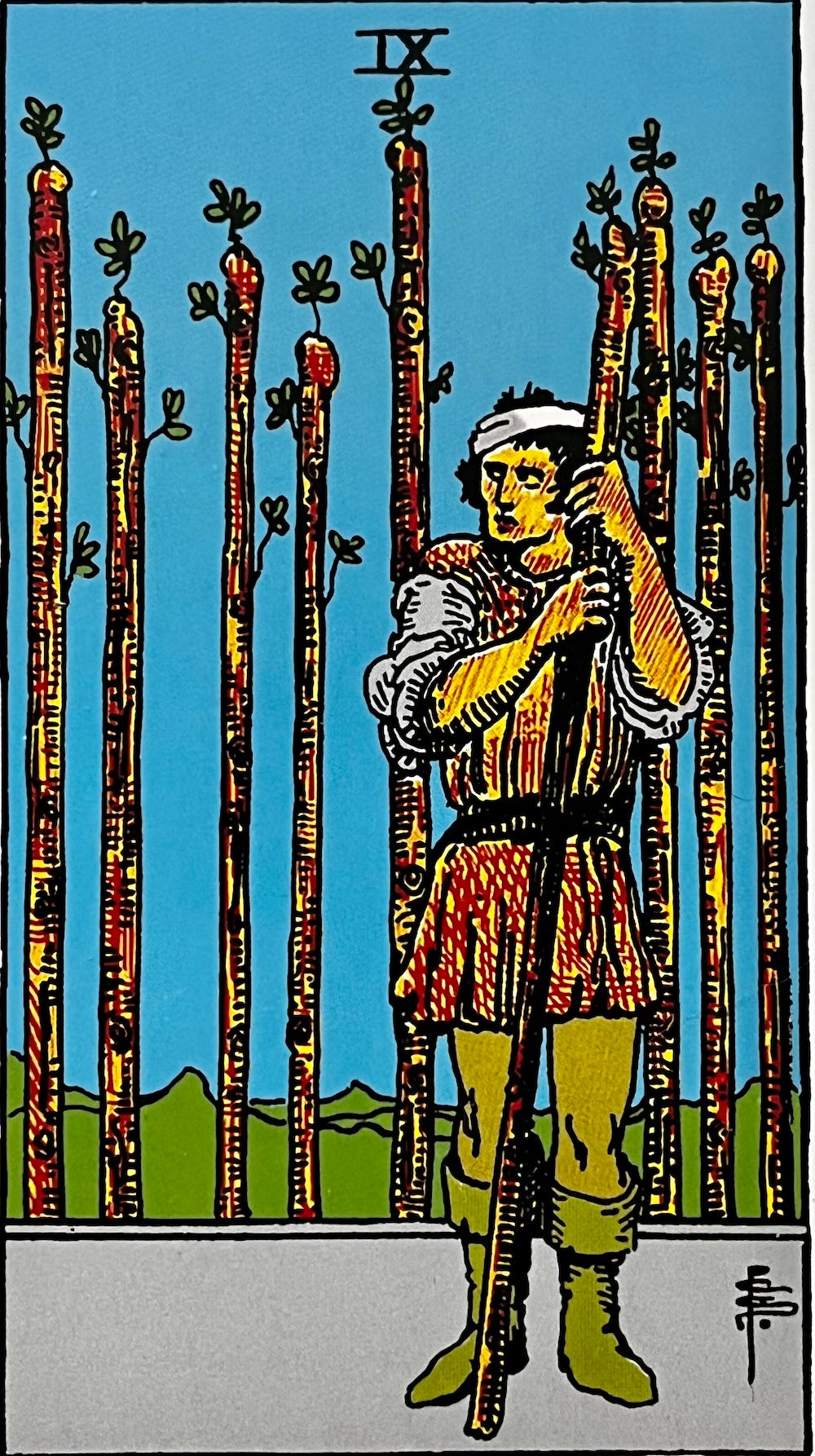 Nine of Wands — A battle weary mans satnd holding a wand. behind him are eight more wands set up like a fence.