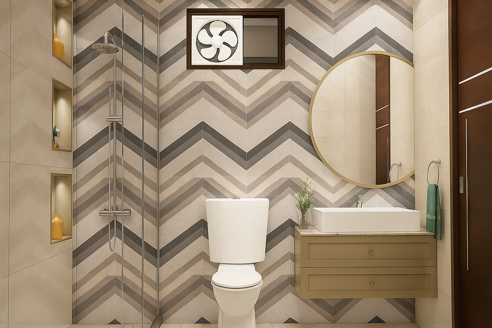 A modern bathroom interior featuring a bold chevron-patterned accent wall in neutral shades of beige and gray. The space includes a sleek wall-mounted vanity with a rectangular basin sink, topped by a large round mirror. A white toilet is centered against the feature wall, while a glass-enclosed shower with a rain shower head is placed on the left. Built-in niches with soft lighting display decor pieces, adding both function and elegance.