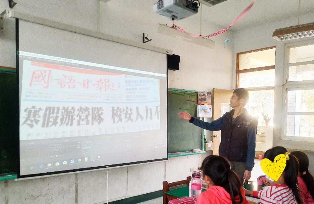 Students reading the same copy of a Chinese newspaper together, projected by a refurbished document camera.