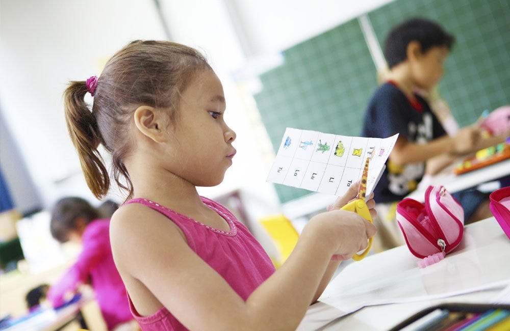 An primary school girl is cutting a piece of paper during class at Deutsche Schule Jakarta