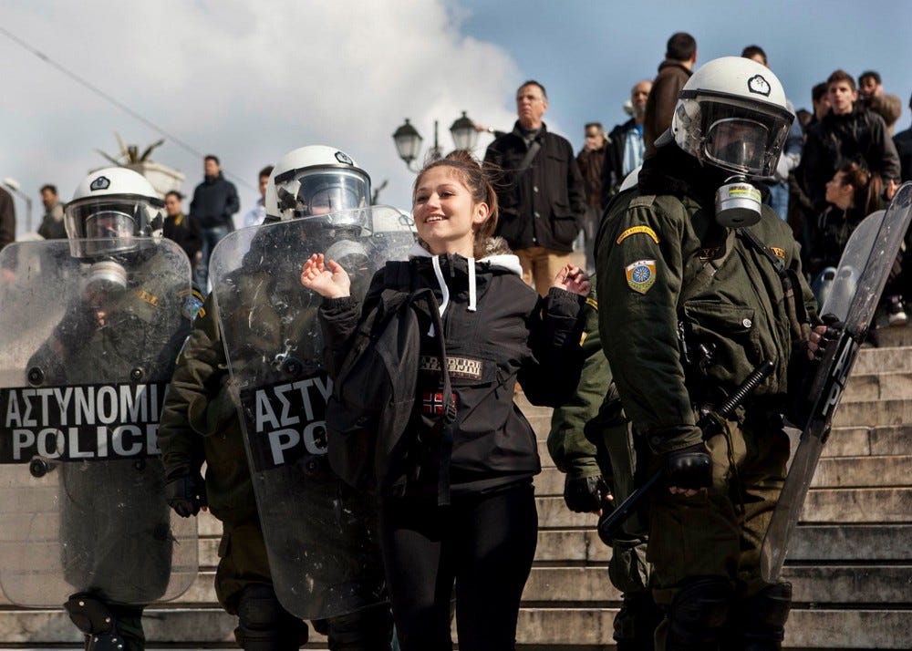 A student protester taunts Greek riot police in front of the Hellenic Parliament during Eurozone Crisis Protests in 2012.