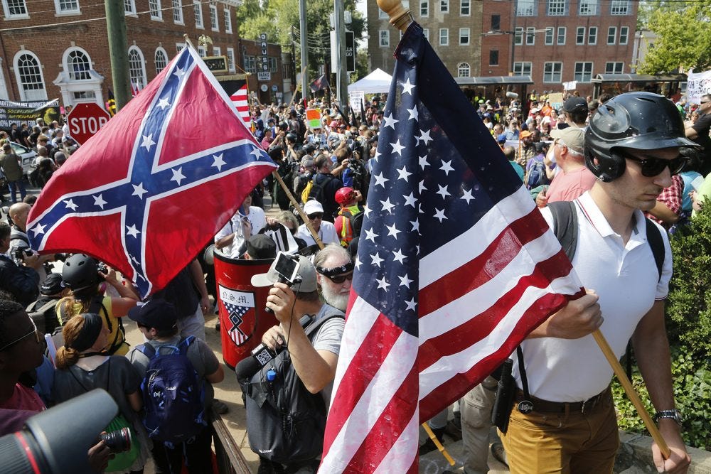 A crowd of white nationalists gather. A confederate flag and an American flag are visible.