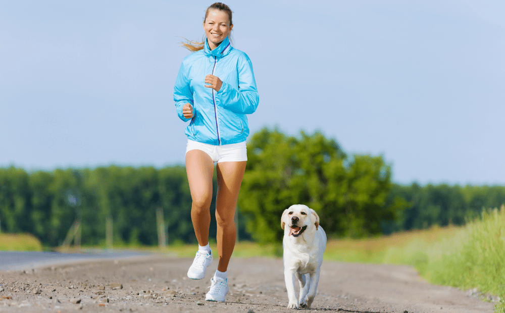 Woman encouraging physical activity by jogging with her dog on a sunny day.