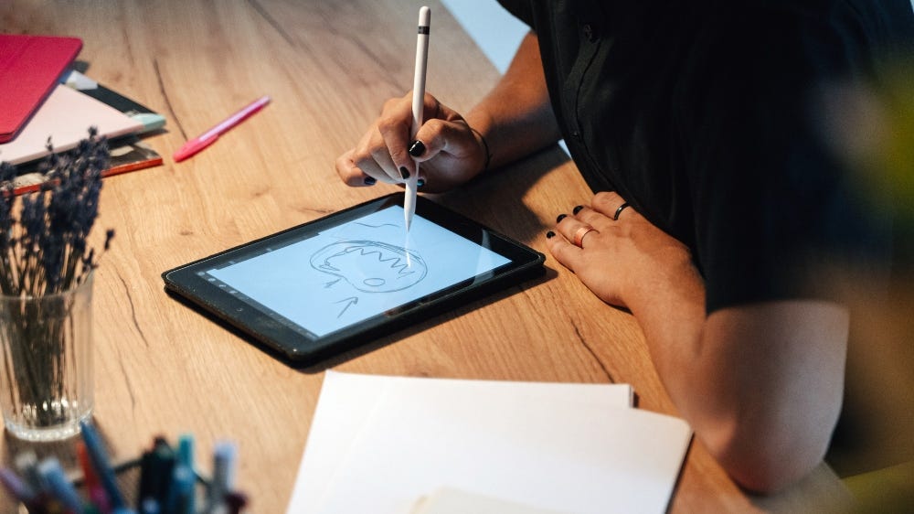 Fotografia de uma pessoa desenhando em seu tablet.