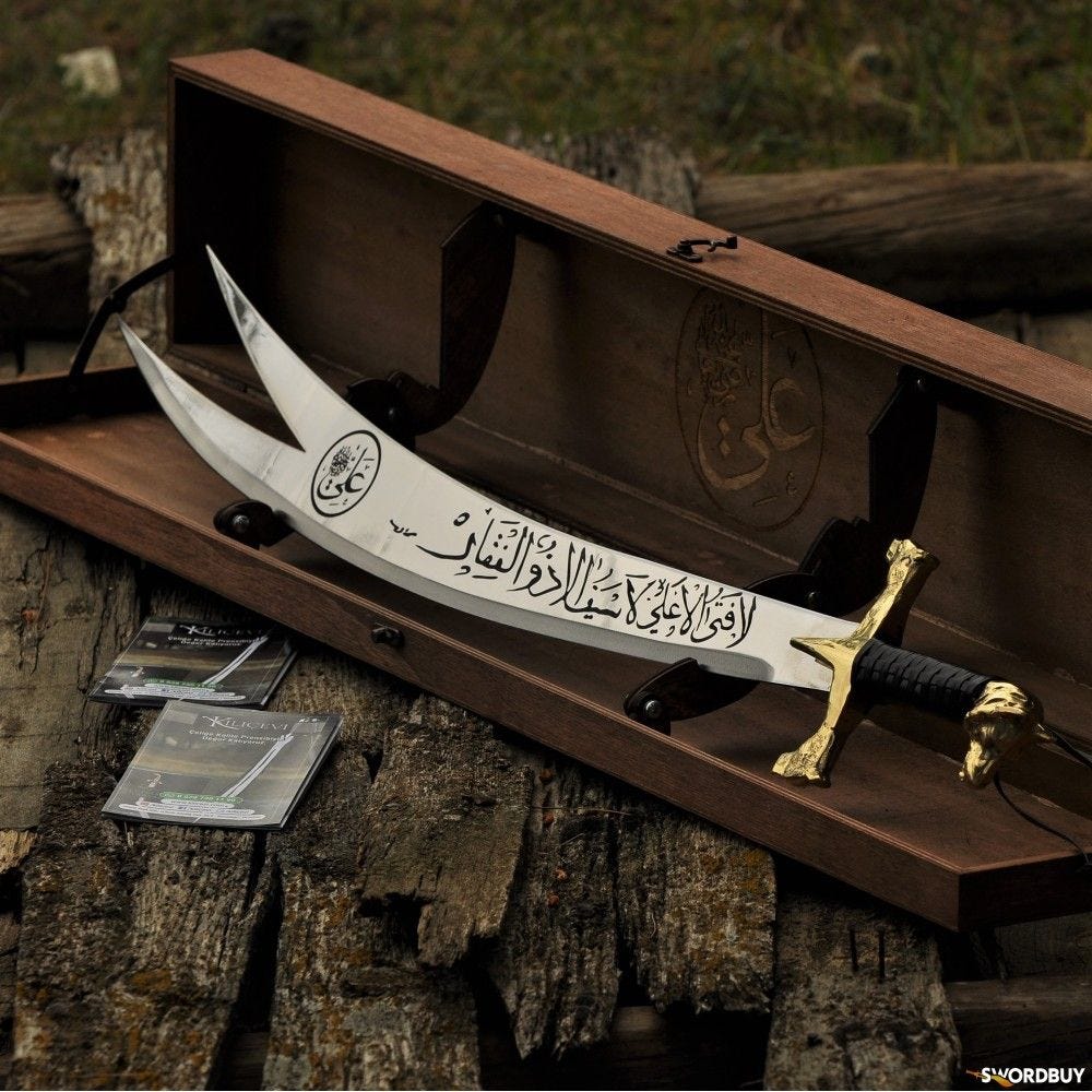 The iconic double-pointed blade of Zulfiqar, a sword revered for its power and association with justice. It is intricately engraved with Arabic inscriptions.
