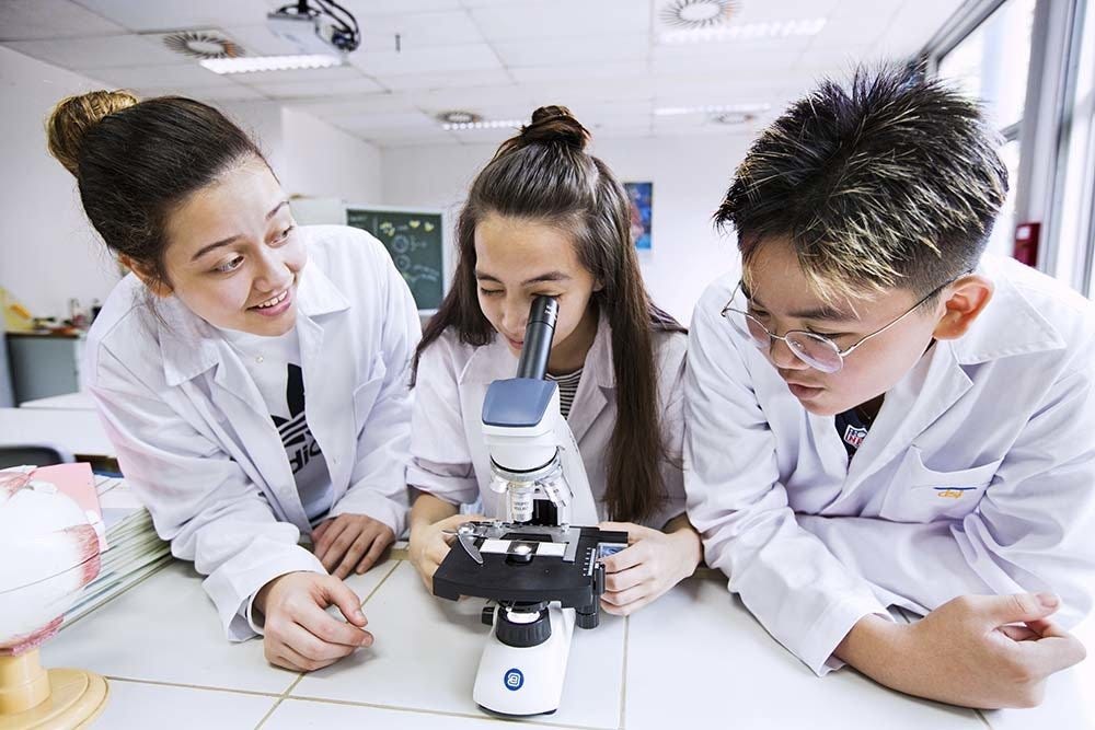 Science students looking through microscope at Deutsche Schule Jakarta