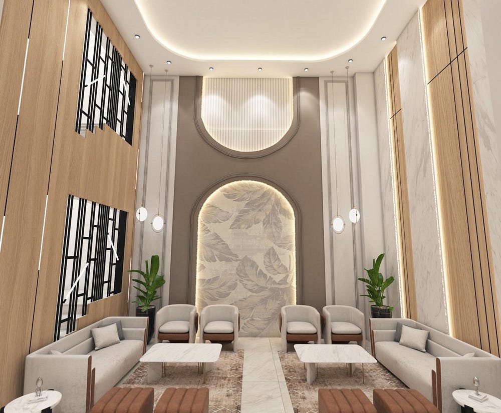 A sophisticated hotel lounge featuring high ceilings, soft cove lighting, and elegant wall detailing with a leaf-pattern accent panel. Comfortable grey sofas and armchairs with marble-top coffee tables create an inviting seating arrangement. Warm wooden panels with black geometric accents and indoor plants add balance and style. The space exudes modern luxury and relaxation, offering guests a serene environment to unwind or socialize.