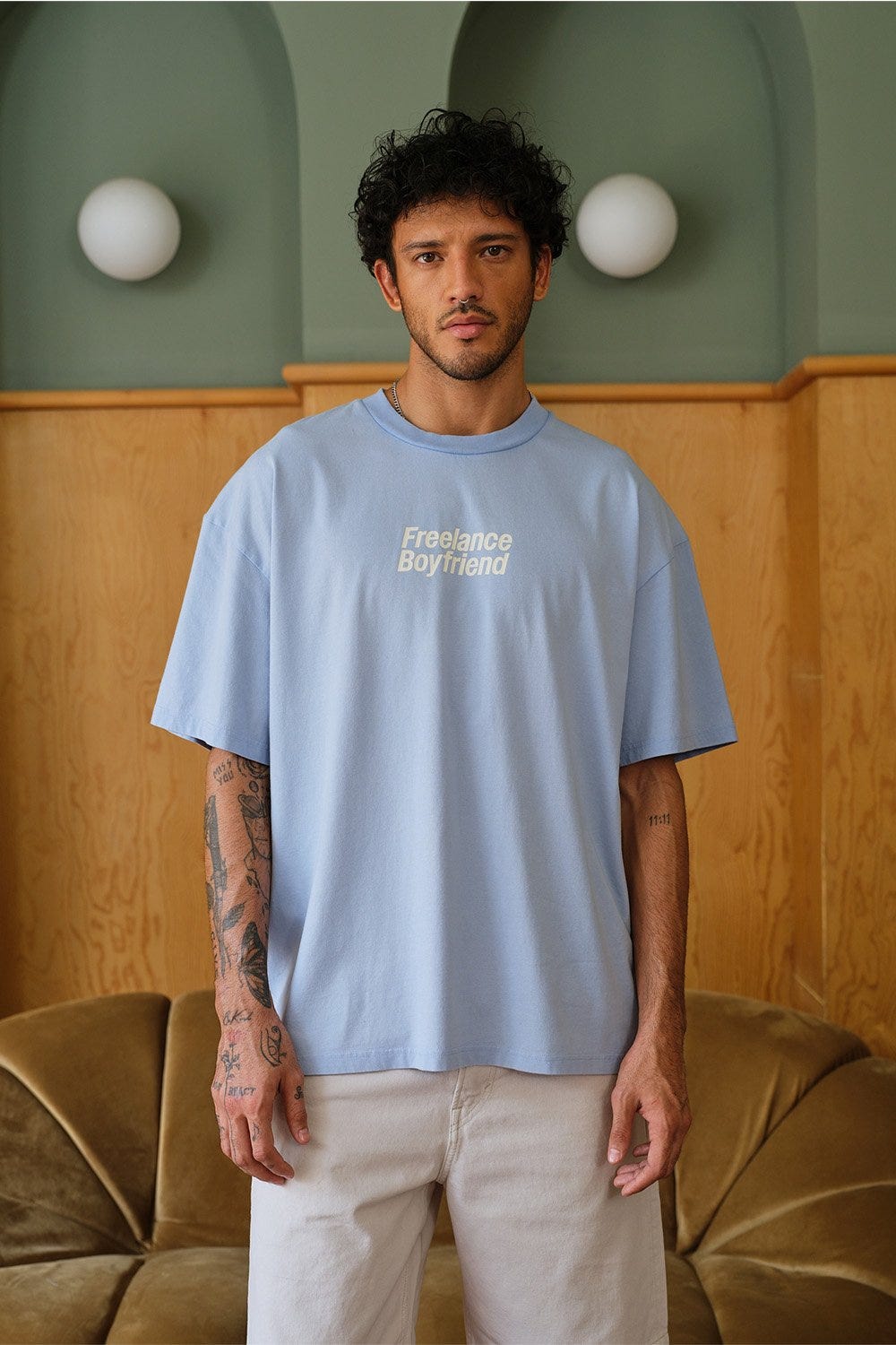 A male model posing in a Blue Freelance Boyfriend Oversized T-shirt with ‘freelance boyfriend’ written on it.
