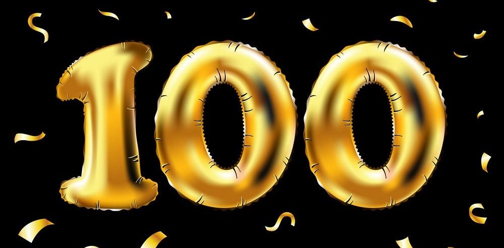 “100” written in large gold balloons with gold confetti