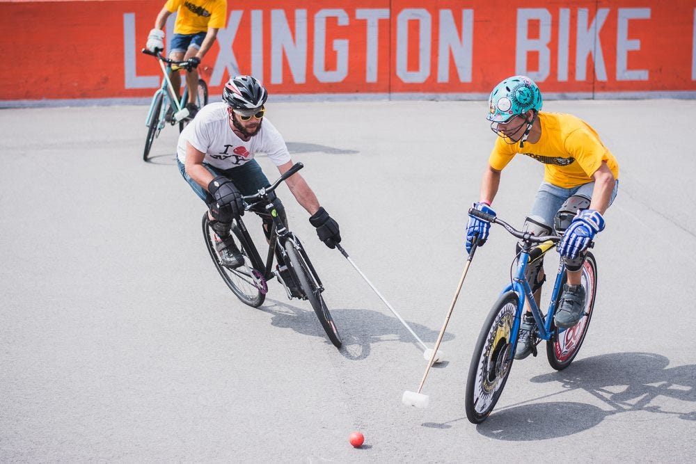 two bike polo players playing the ball