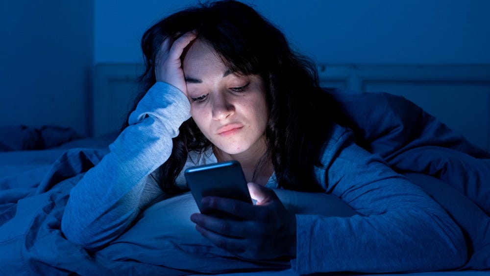 A girl restlessly scrolling through phone at night.
