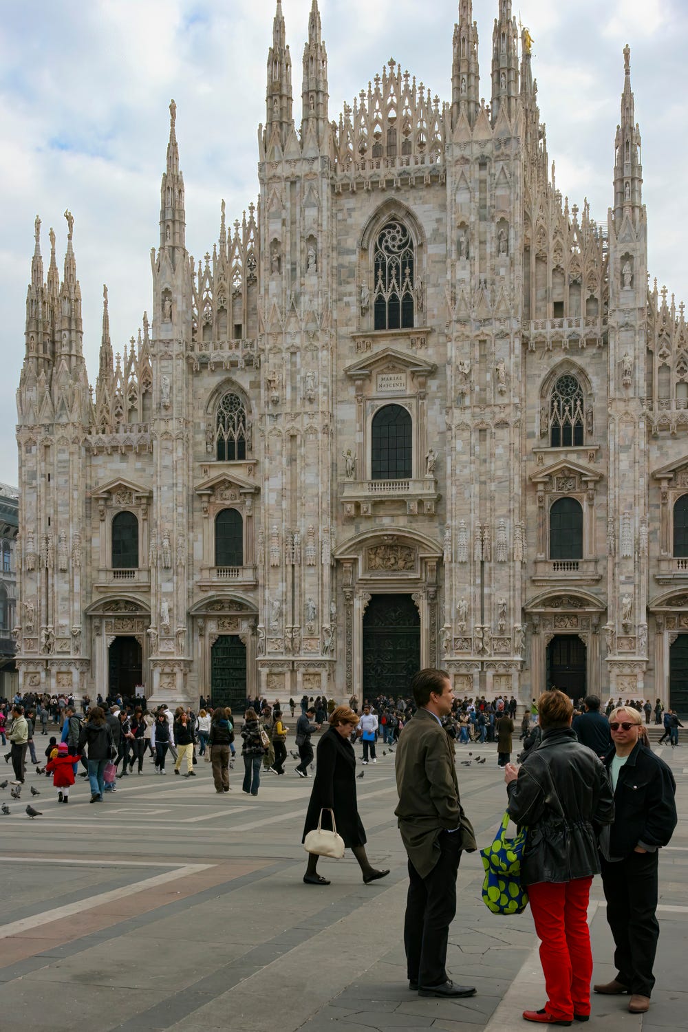 Hundreds of people standing around in the piazza in front of the Milan Cathedral.