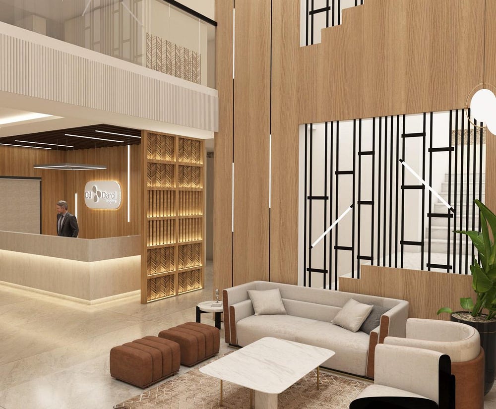 A contemporary corporate reception area featuring a sleek reception desk with soft backlighting and a logo wall behind it. The space includes a stylish lounge with a cream sofa, armchairs, and a marble-top coffee table, paired with brown ottomans. Warm wooden wall panels, decorative black metal partitions, and indoor plants add sophistication. Soft ambient lighting and modern finishes create a professional yet welcoming atmosphere for visitors.